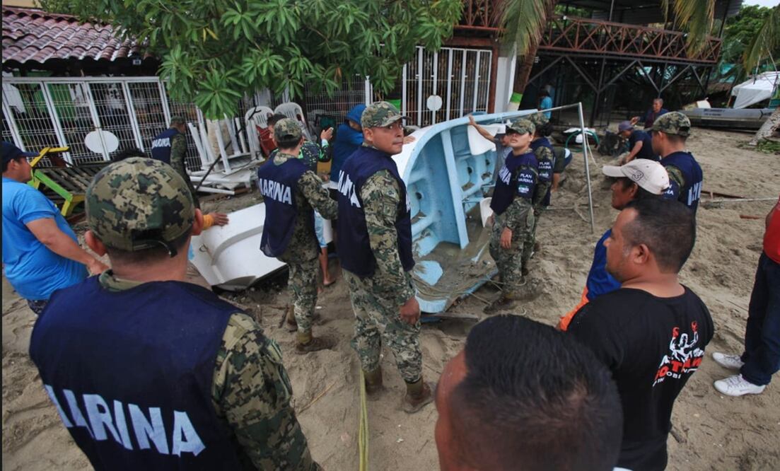 Elementos de la Marina ayudan a pescadores a sacar sus embarcaciones que quedaron enterradas bajo la arena y a retirar la basura que devolvió el mar en Puerto Escondido, tras el impacto de “Erick” en Oaxaca, el 19 de junio de 2025. Foto: Edwin Hernández/EL UNIVERSAL