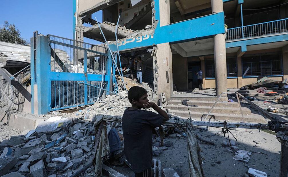 Un niño palestino se encuentra cerca de los escombros de una escuela del OOPS dañada tras un ataque aéreo israelí. Foto: EFE