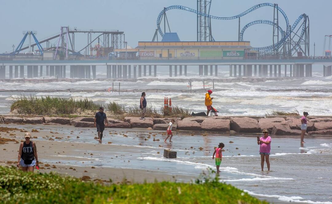 La gente se encuentra en el alto oleaje antes de que la tormenta tropical Beryl toque tierra en Matagorda. FOTO: EFE