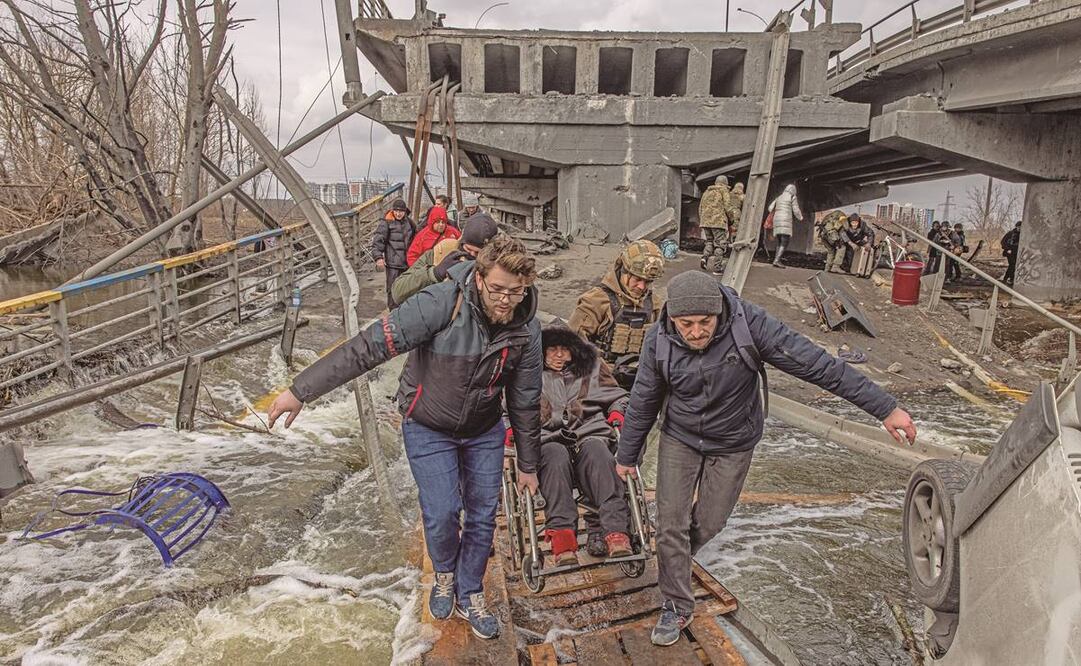 Residentes en su intento por cruzar un puente destruido por los enfrentamientos entre el ejército ruso y ucraniano, en Irpin, región de Kiev. Roman Pilipey/EFE 