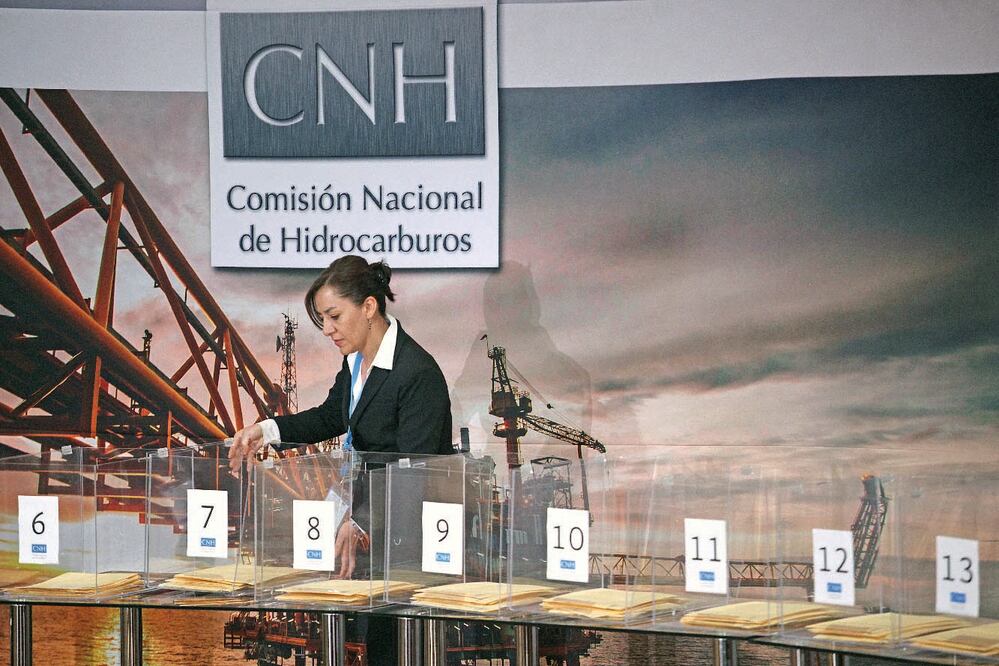 Una edecán coloca una de las urnas durante la primera licitación de la Ronda Uno de hidrocarburos en el auditorio de Nacional Financiera