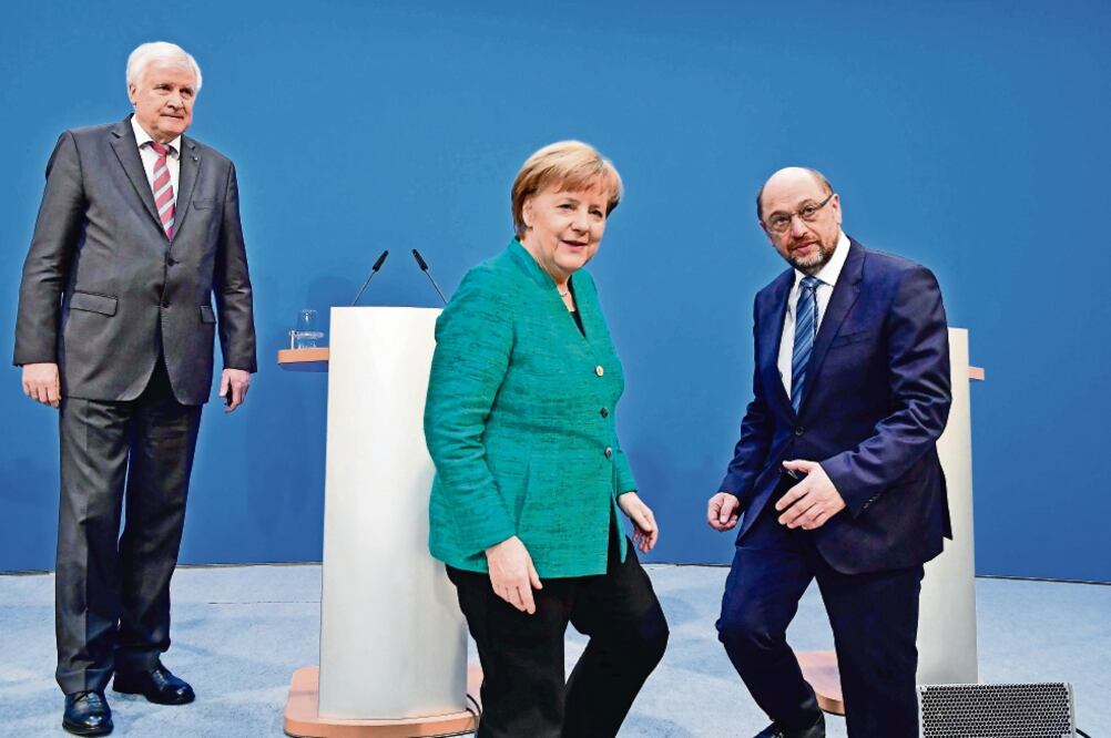 Horst Seehofer, líder del CSU; la canciller alemana Angela Merkel y Martin Schulz, de la CDU, tras sellar un acuerdo de gobierno, en Berlín (TOBIAS SCHWARZ. AFP)