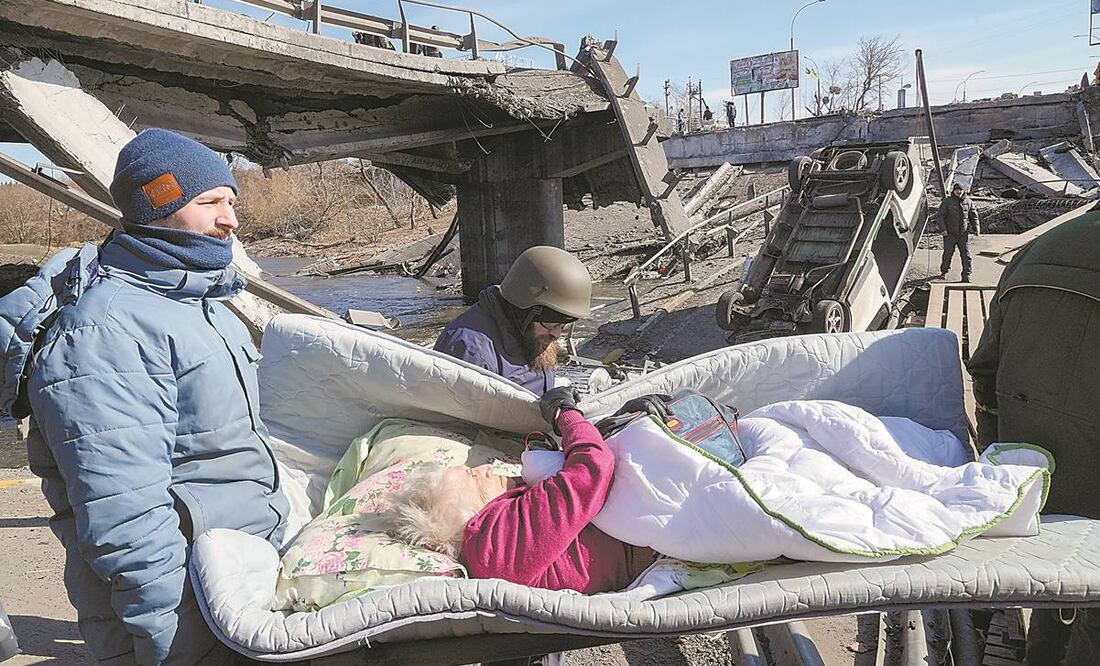 Voluntarios desalojan a una ucraniana mayor en Irpin, un suburbio de Kiev que lleva días bajo el impacto del bombardeo ruso. Foto: EFREM LUKATSKY/ AP.