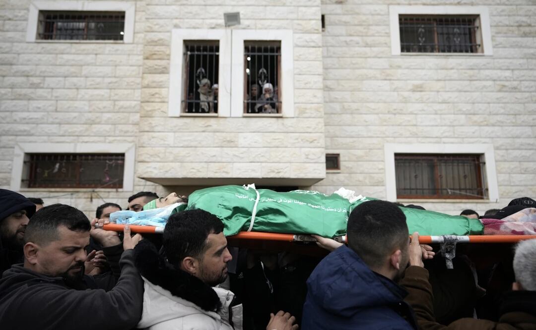 Dolientes palestinos cargan el cuerpo de Muhammad Jalamneh, envuelto en la bandera del grupo armado Hamas, durante su funeral tras ser asesinado en un asalto a hospital Ibn Sina en la localidad cisjordana de Yenín. Foto: AP