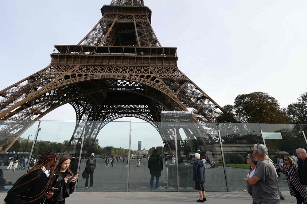 Los visitantes pasan junto a un cartel que dice "Debido a una huelga, la Torre Eiffel está cerrada. Pedimos disculpas", con la Torre Eiffel al fondo, en medio de una jornada de huelga nacional convocada por los ocho sindicatos más grandes de Francia para exigir medidas de "justicia social", en París. Foto: AFP