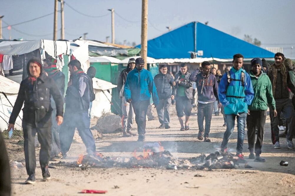 Migrantes caminan por el campamento de refugiados en Calais, Francia, conocido como "la jungla", en el cual hubo enfrentamientos ayer debido a la molestia ante el desalojo de migrantes (JOEL GOODMAN. XINHUA)