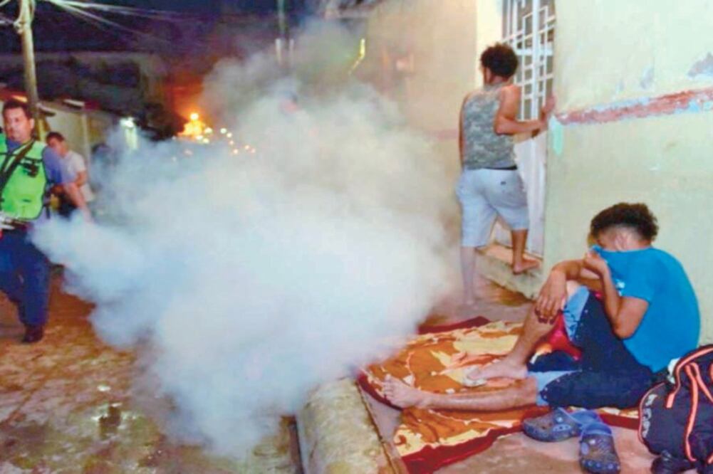 Dos hombres con chalecos verdes y el logo de Chiapas nos Une pasaron con una bomba aspersora y lanzaron clorpirifos en calles de Huixtla. La sustancia química se usa para el combate del zancudo. (ESPECIAL)