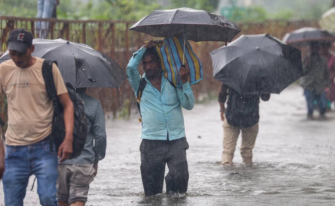 La gente camina por una calle anegada durante las fuertes lluvias en Bombay, India. Foto: EFE