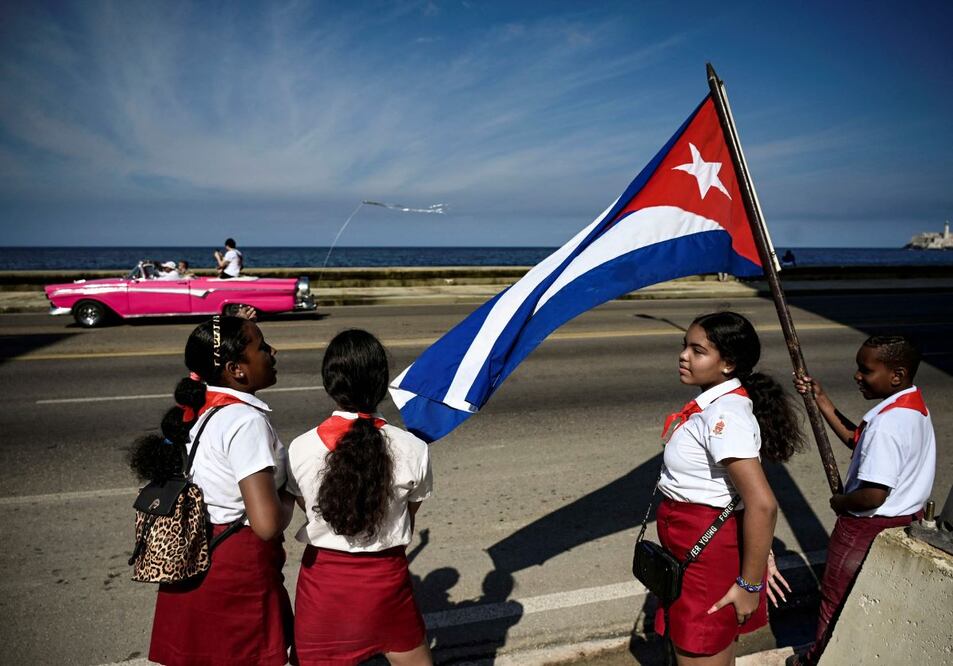 Escolares cubanos ondean una bandera del país, en el 65 aniversario de la entrada de Fidel Castro a La Habana, que marcó el triunfo de la Revolución cubana. Cuba inicia este 2024 con una dramática alza en el precio de la gasolina. FOTO: YAMIL LAGE. AFP