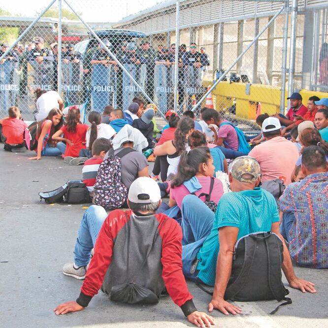 Familias de migrantes centroamericanos permanecen sentados afuera de la estación fronteriza de Puente Nuevo, en Matamoros, Tamaulipas. ABRAHAM PINEDA. EFE