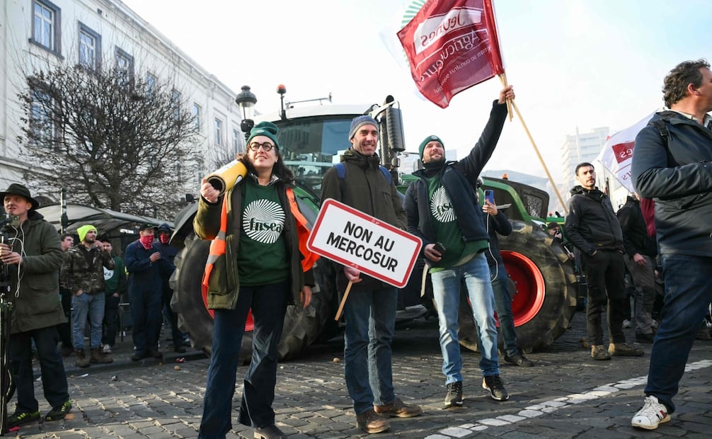 Manifestantes portan pancartas con la leyenda "No al Mercosur" y banderas del principal sindicato agrícola francés, FNSEA (Federación Nacional de Sindicatos de Explotantes Agrícolas) y de Jóvenes Agricultores (JA), cerca del Parlamento Europeo, en la Plaza de Luxemburgo, durante una protesta campesina para denunciar las reformas de la Política Agrícola Común (PAC) y acuerdos comerciales como el Mercosur. Esta protesta se celebró en Bruselas el 18 de diciembre de 2025. La protesta fue organizada por Copa-Cogeca, la principal asociación que representa a agricultores y cooperativas agrícolas en la UE. Los agricultores de la UE, especialmente en Francia, temen que el acuerdo con el Mercosur —que se debatirá en la reunión de líderes de la UE— los vea perjudicados por el flujo de productos más baratos procedentes del gigante agrícola Brasil y sus vecinos. También se oponen a los planes de la Comisión Europea para reformar los enormes subsidios agrícolas del bloque de 27 países, por temor a que se reduzca su flujo de fondos. Foto: AFP