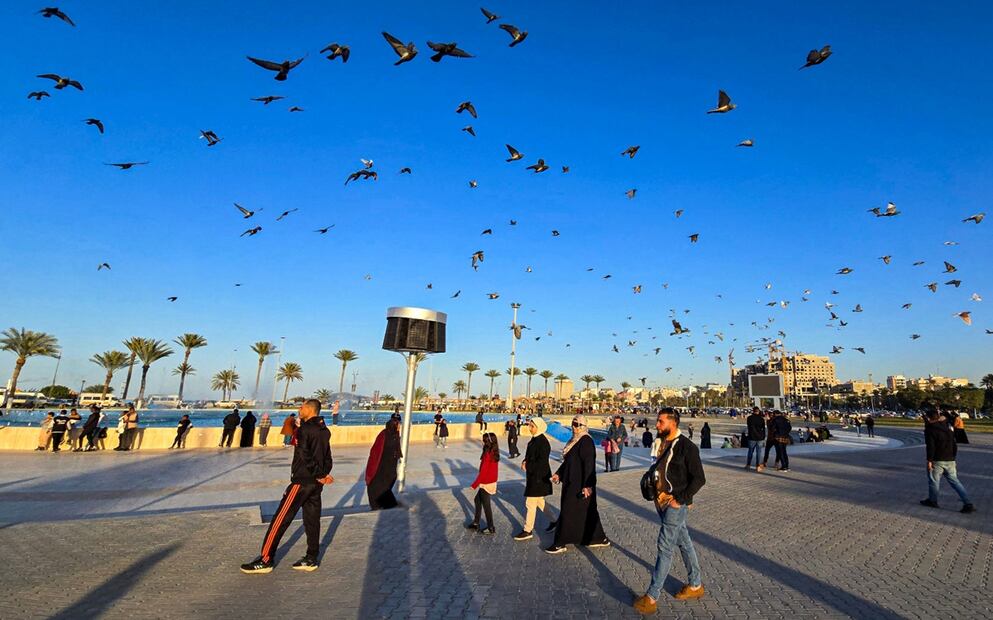 Palomas vuelan sobre la gente que camina junto a la fuente de la Plaza de los Mártires en Trípoli, capital de Libia, el 15 de febrero de 2025. Foto: AFP