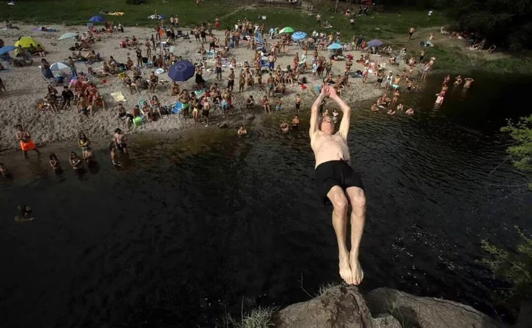 Alberto Frascaroli, conocido como el "Abuelo Clavadista", realiza uno de sus saltos en la playa Miami de Santa Mónica, en Córdoba, Argentina. FOTO: LA NACIÓN