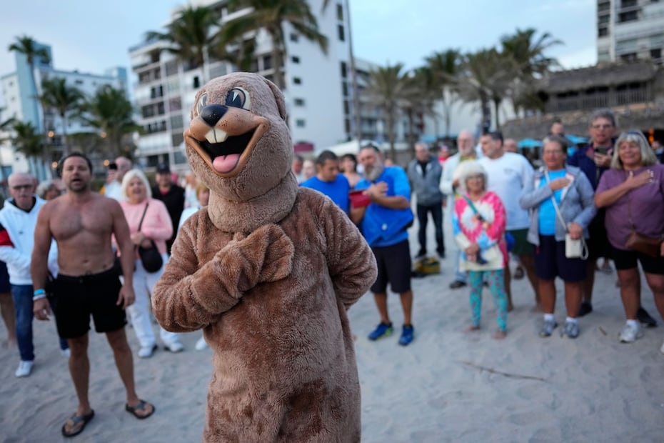 La gente canta el himno nacional junto con una versión local de Punxsutawney Phil, mientras se reúnen en la playa para celebrar el Día de la Marmota en Florida,  después del amanecer del viernes 2 de febrero de 2024. Foto: AP
