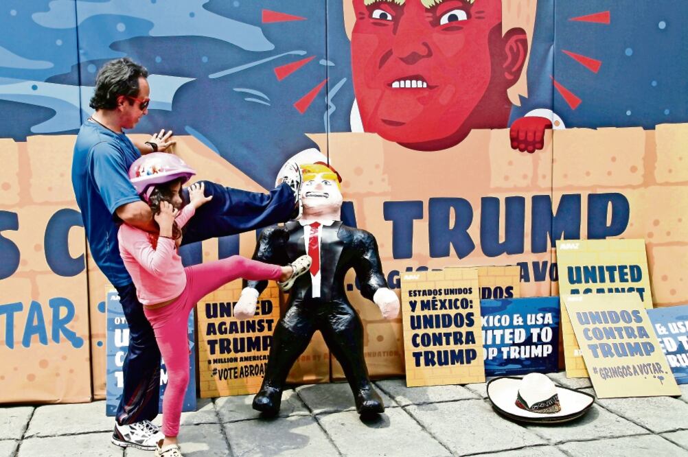 Una niña y su papá patean una piñata de la figura de Donald Trump que tiene al fondo un muro simbólico, en la ciudad de México. (FOTO: ARCHIVO AP)