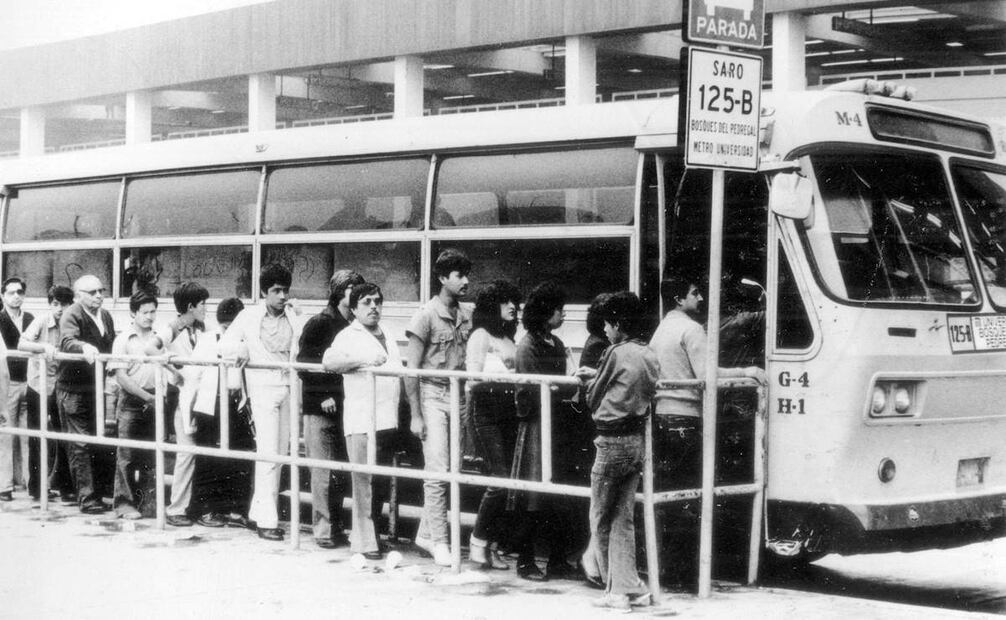 Varias personas son captadas abordando un autobús de la extinta Ruta 100 en una fotografía tomada en la década de los ochenta. Al fondo se encuentra la estación terminal Universidad de la línea 3 del Metro. Crédito: Colección Villasana.