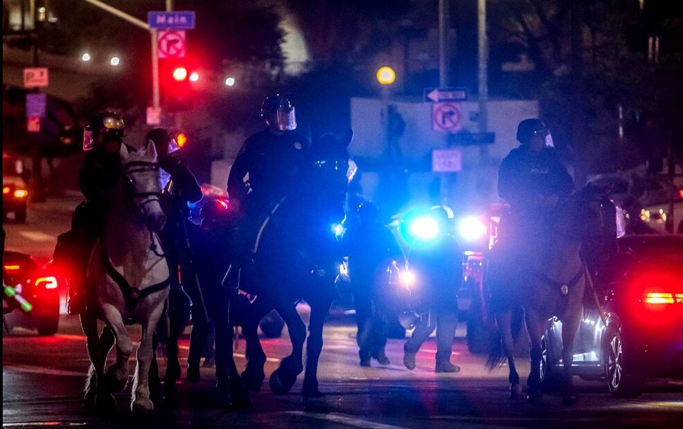 Oficiales de la montada del Departamento de Policía de Los Ángeles cabalgan en el centro de la ciudad, tras la entrada en vigor del toque de queda. Foto: AFP