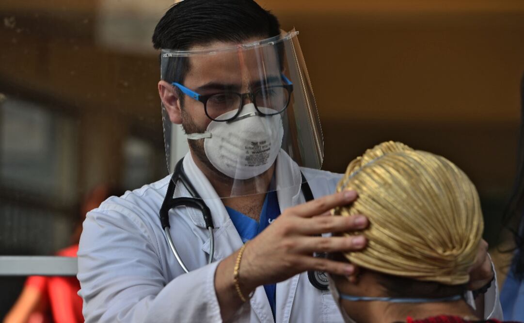 A medical doctor wears a face mask and shield as he examines a patient with symptoms of the new coronavirus - Photo: Orlando Sierra/AFP