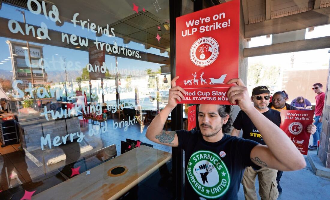 Baristas de Starbucks durante las protestas afuera de una sucursal de la cadena de cafeterías en Burbank, California. Foto: Damian Dovarganes | AP (23/12/2024)
