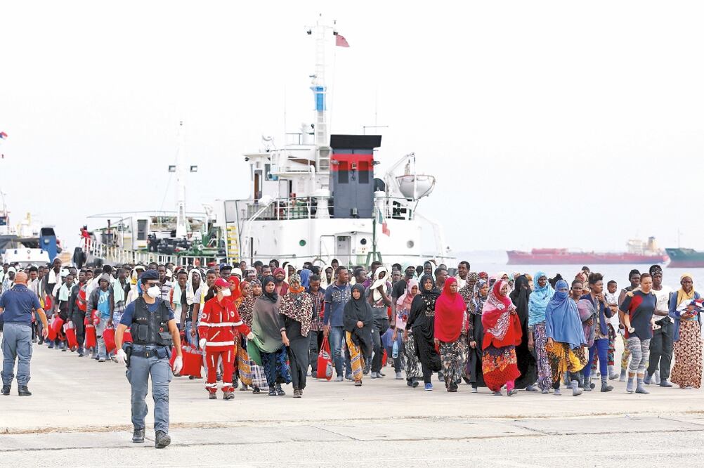 Migrantes caminan sobre el muelle del puerto siciliano de Augusta, tras su llegada en un barco de Médicos Sin Fronteras que transportaba a unas 320 personas (ANTONIO PARRINELLO. REUTERS)