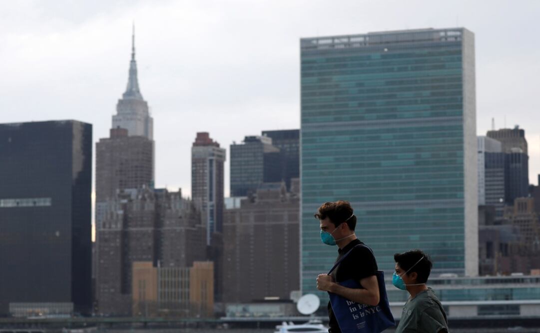 People in protective masks walk in front of the Manhattan skyline along the waterfront of Long Island City as the coronavirus disease (COVID-19) outbreak continues in the Queens borough of New York City, U.S. - Photo: Andrew Kelly/REUTERS