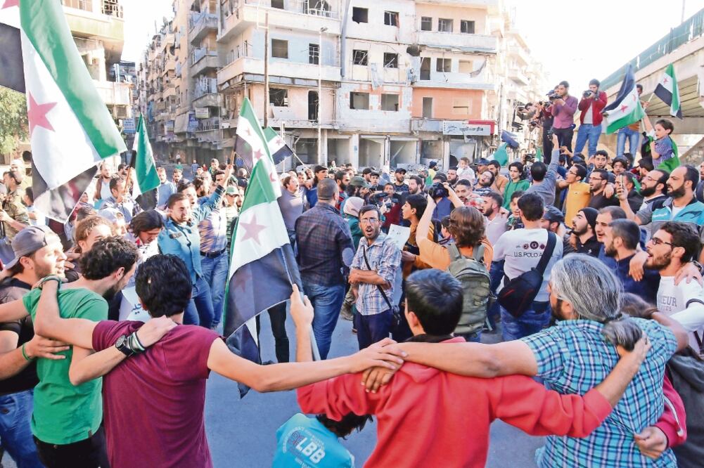 Manifestantes con banderas del rebelde Ejército Sirio Libre protestan contra el desalojo de civiles de Aleppo. Aseguran que es una “artimaña” del gobierno (ABDALRHMAN ISMAIL. REUTERS)