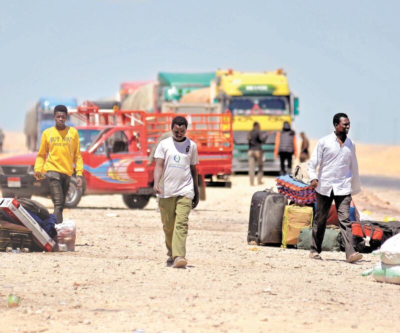 Personas caminan por una carretera cerca de sus camiones después del cierre de la frontera entre Sudán y Egipto. EFE
