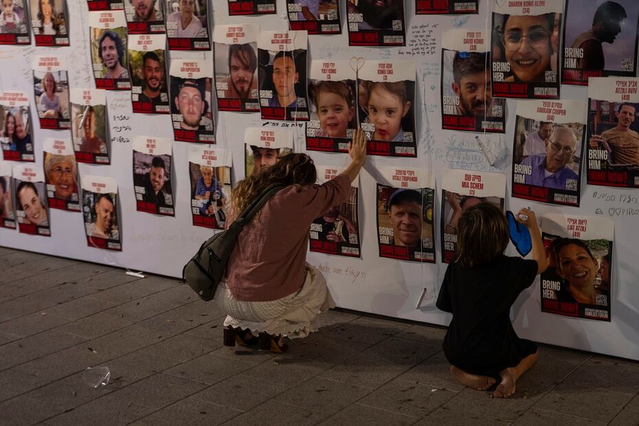 Una mujer israelí toca con la mano fotografías de israelíes desaparecidos y cautivos en Gaza, exhibidas en una pared en Tel Aviv. Foto: AP