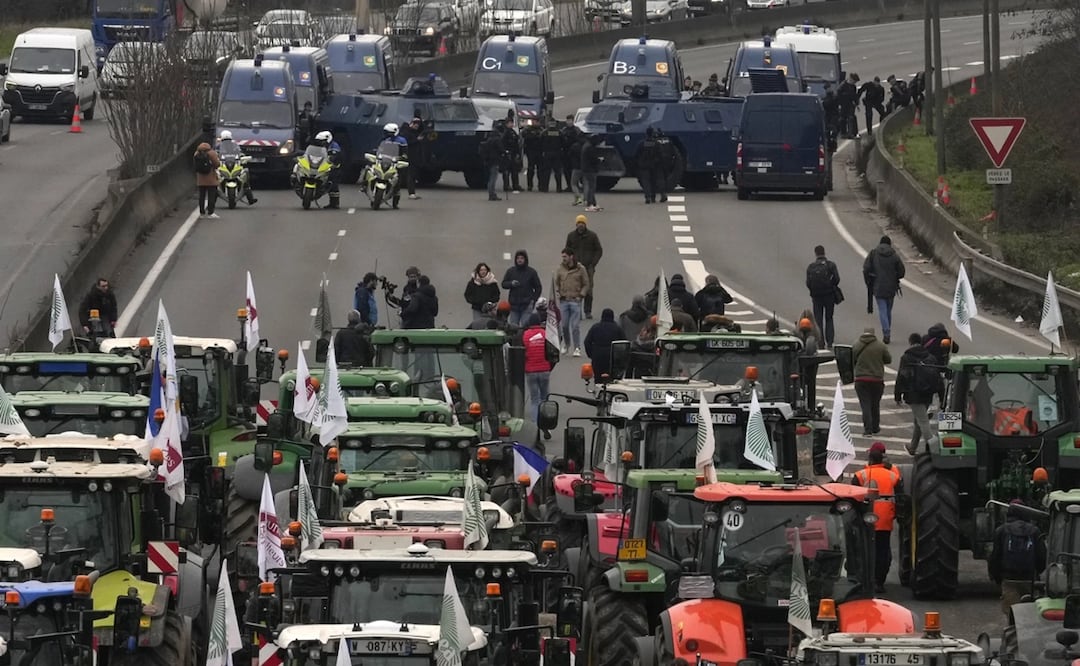 Tractores colocados ante vehículos de las fuerzas de seguridad en una autopista cortada. Foto: AP