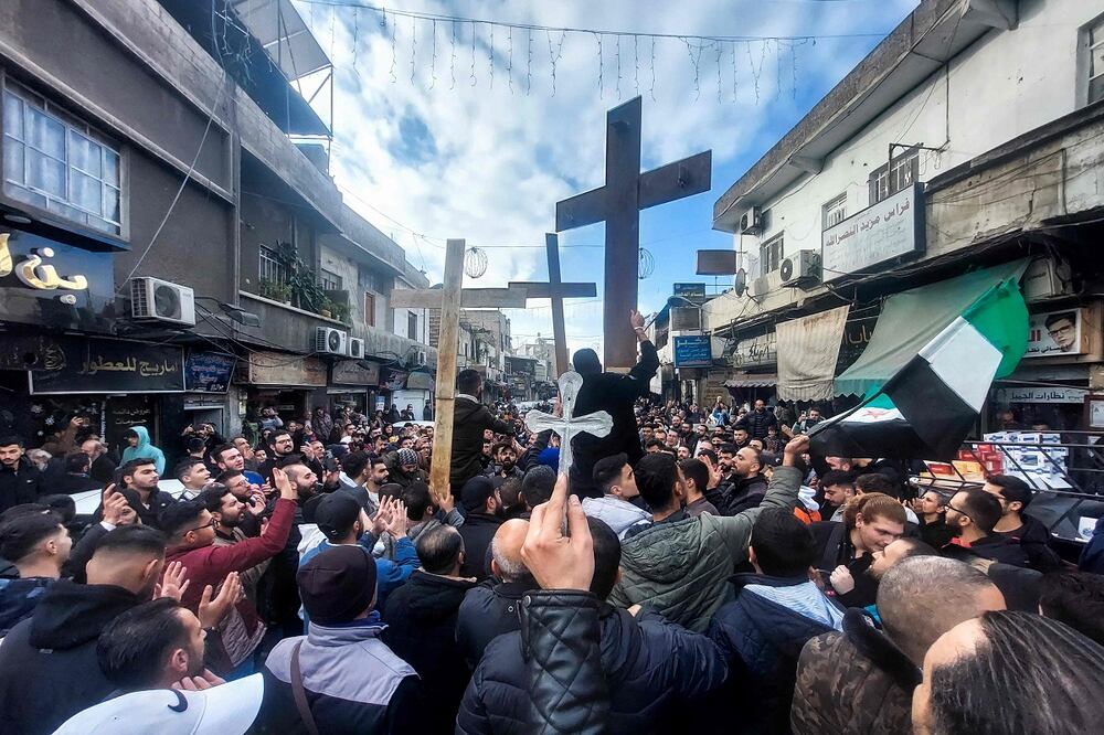 Los sirios cristianos levantan cruces mientras se manifiestan en la zona de Duweilaah en Damasco el 24 de diciembre de 2024 para protestar por la quema de un árbol de Navidad cerca de Hama, en el centro de Siria. Foto: AFP