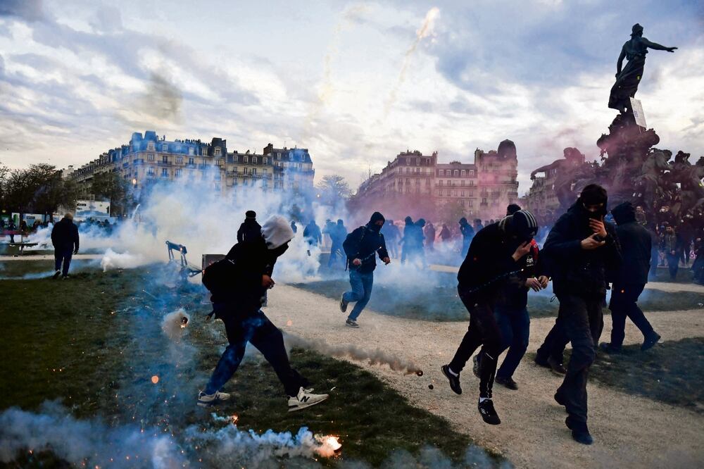 Manifestantes contra la reforma de pensiones, entre botes de gas lacrimógeno, en París. Foto: Julien de Rosa/AFP