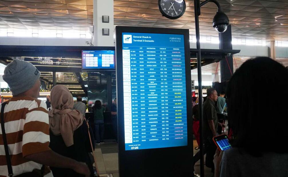 Pasajeros miran una pantalla de información del Aeropuerto Internacional  Soekarno-Hatta, la cual muestra cancelación de vuelos debido a la erupción del volcán Anak Krakatau. Foto: Tatan Syuflana / AP