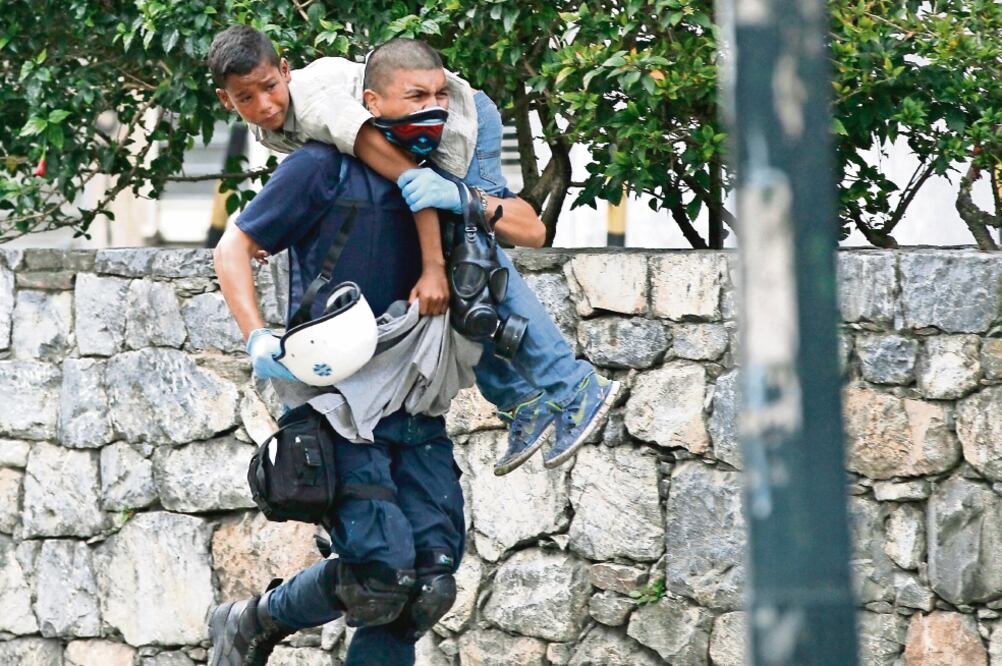 Un médico carga a un niño que resultó afectado por los gases lacrimógenos lanzados durante la protesta de ayer en Caracas, Venezuela. (ARIANA CUBILLOS. AP)