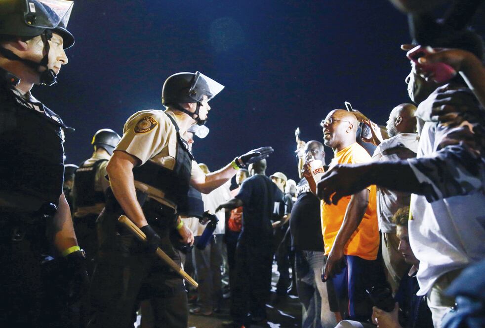 Oficiales y manifestantes se enfrentan, en la avenida West Florissant, en Ferguson, en horas de la madrugada del martes. La tensión es elevada, a un año de la muerte de Michael Brown (JEFF ROBERSON. AP)