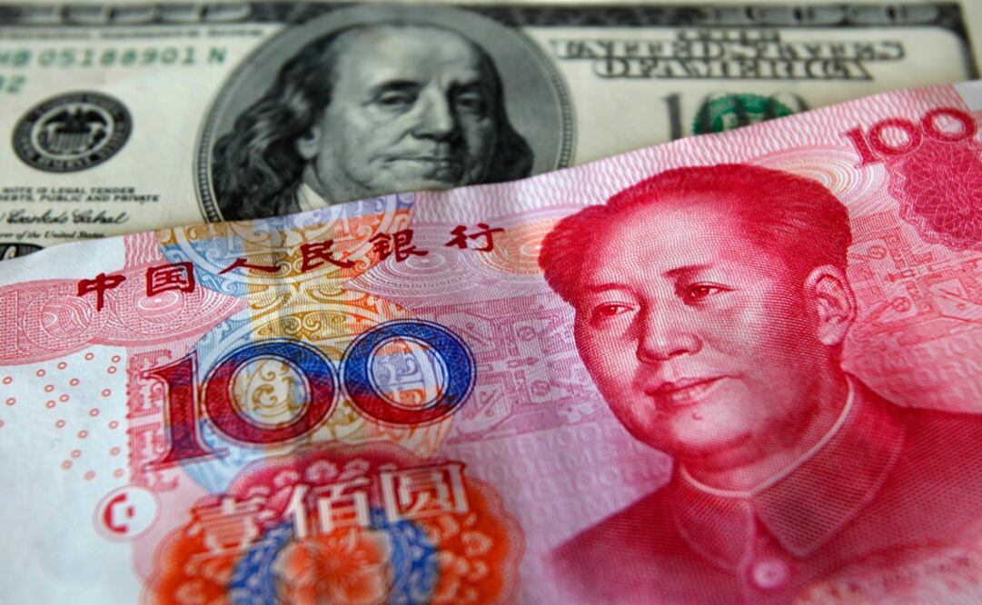 A yuan banknote is displayed next to a U.S. dollar banknote - Photo: Nicky Loh/REUTERS