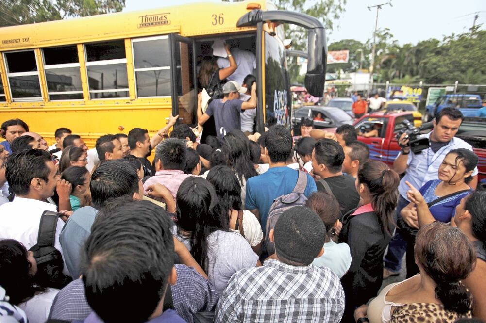 Salvadoreños tratan de subir a un autobús que el gobierno puso a su disposición ayer, en San Salvador, durante el segundo día de paro en el transporte colectivo en el país (JOSÉ CABEZAS. REUTERS)