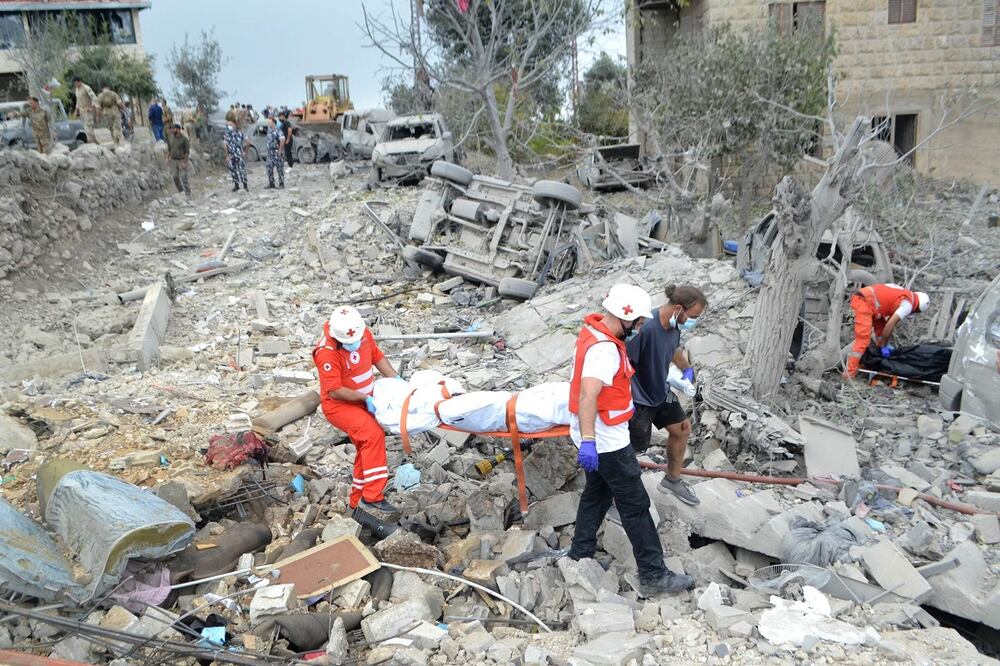 Los paramédicos de la Cruz Roja Libanesa transportan un cuerpo desenterrado entre los escombros en el lugar de un ataque aéreo israelí que tuvo como objetivo la aldea de Aito, en el norte del Líbano, el 14 de octubre de 2024. Foto: AFP/Archivo