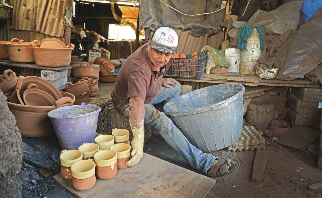 Juan Allende Rojas toma las piezas de barro y las zambulle en la vasija con la greta para lograr el barnizado.