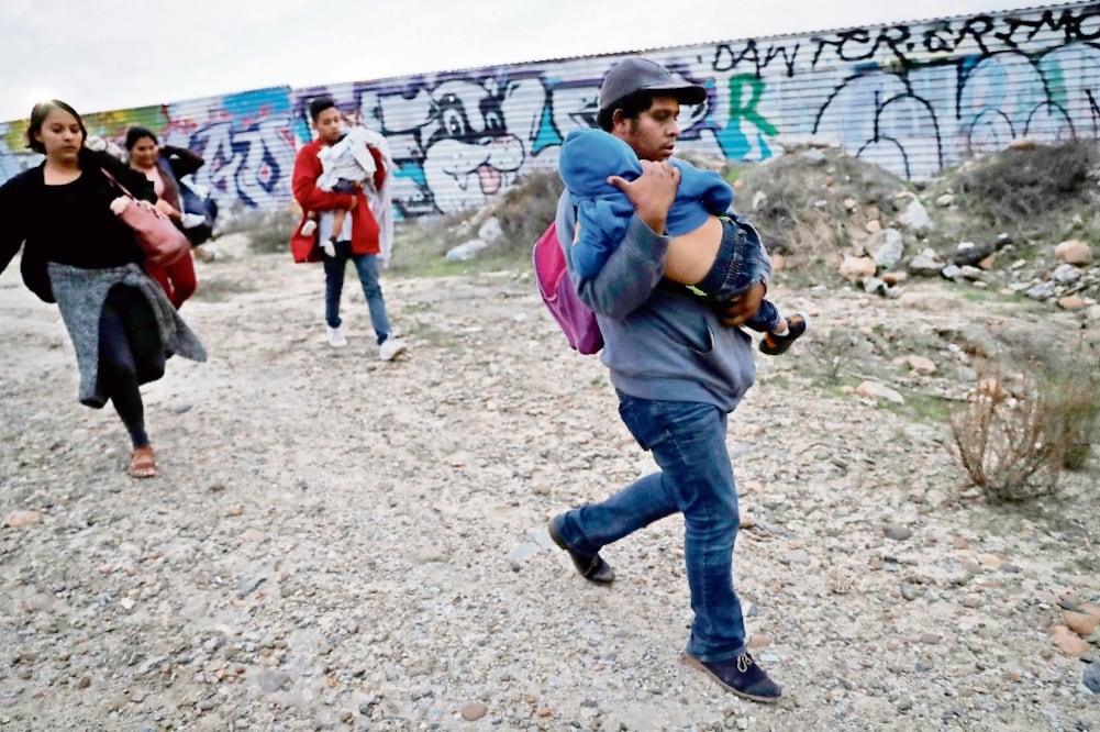 Familias de migrantes caminan a la valla fronteriza para cruzar a Estados Unidos desde Tijuana. (LEAH MILLIS. REUTERS)