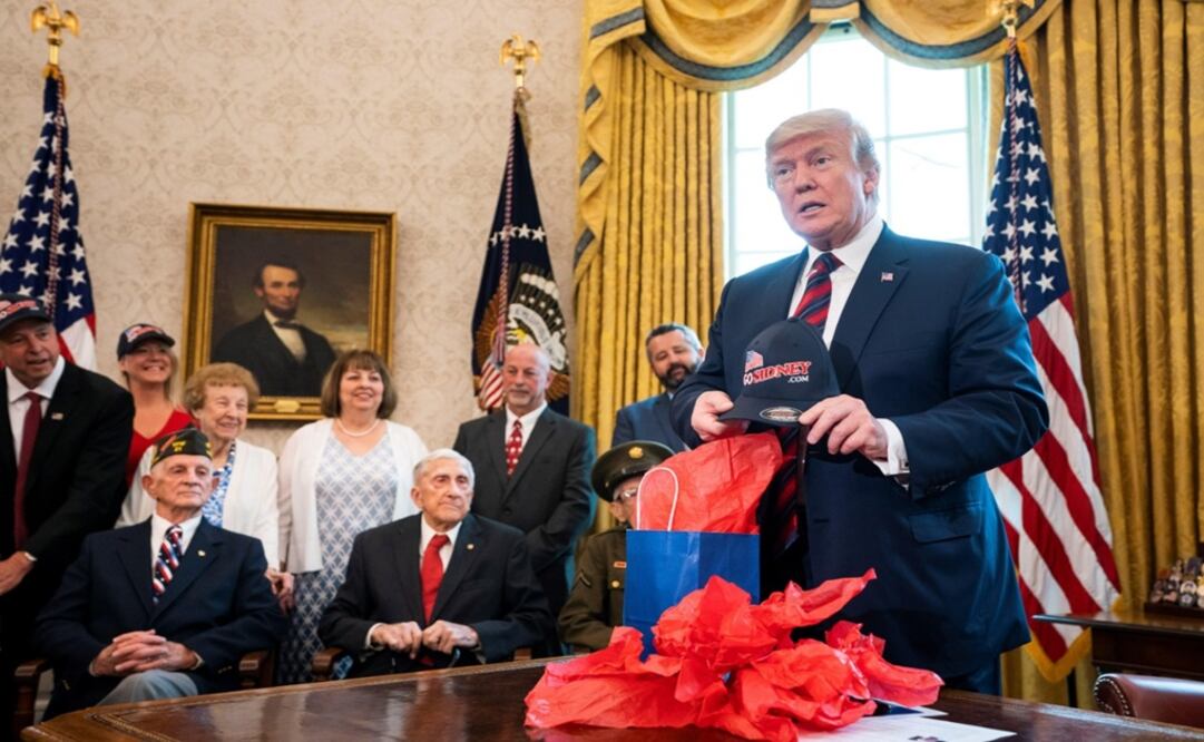 El presidente de los Estados Unidos, Donald J. Trump, abre un regalo durante su reunión con veteranos de la Segunda Guerra Mundial. Foto: EFE