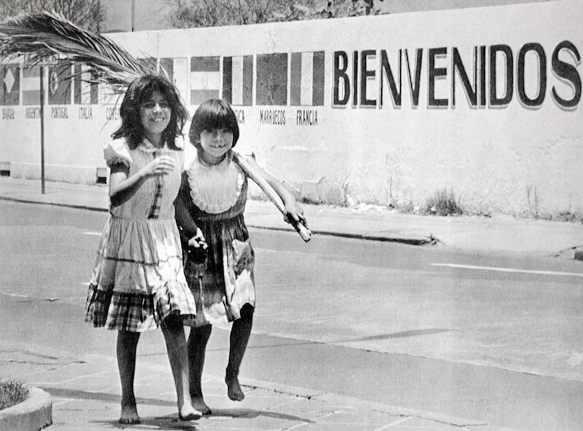 Niñas descalzas frente a una barda decorada. A dos días de la inauguración, EL UNIVERSAL evidenció que “el mundial provocó [un aumento de] inflación, los precios se dispararon y el control de la canasta básica pasó al olvido. Este mundial sólo lo gozan los miembros del comité organizador y policías”. Foto: AP/ESPECIAL.