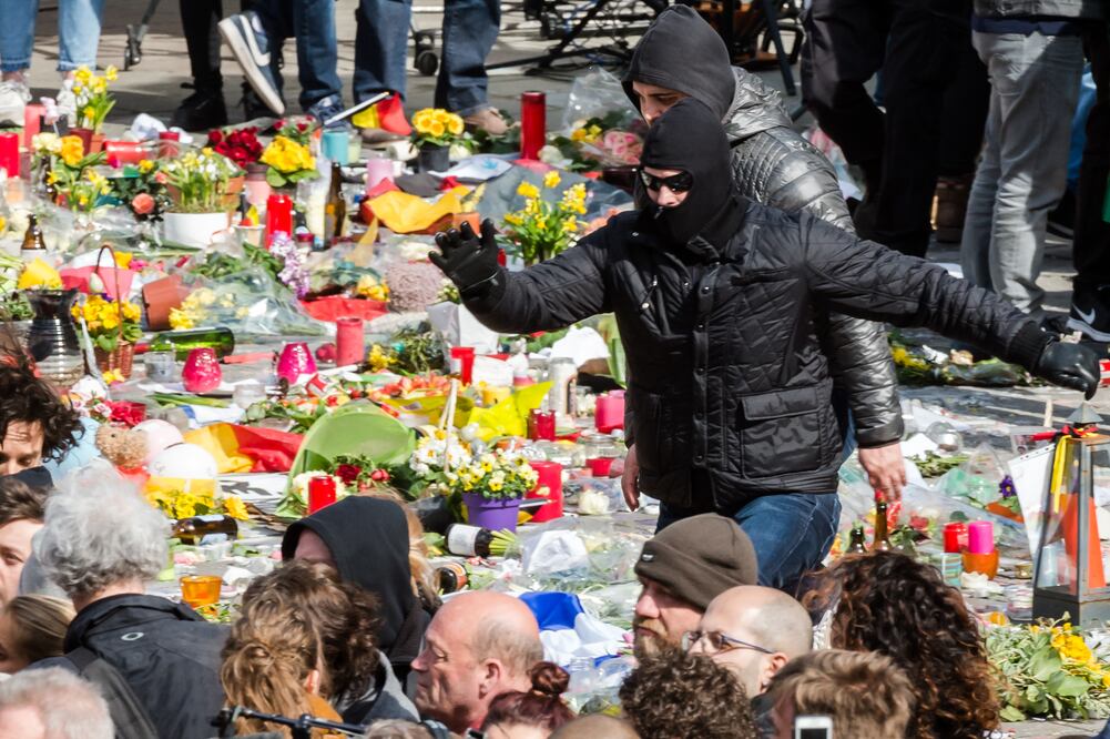 Manifestantes de ultraderecha corren sobre flores y objetos de recuerdo, durante una protesta en el lugar de homenaje a las víctimas de los atentados del 22-M, en la plaza de la Bolsa de Bruselas (Foto: AP)