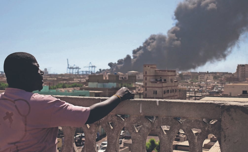 Un testigo observa cómo se elevan columnas de humo tras un ataque con drones en el puerto de Puerto Sudán, el 6 de mayo 2025. Foto: AFP