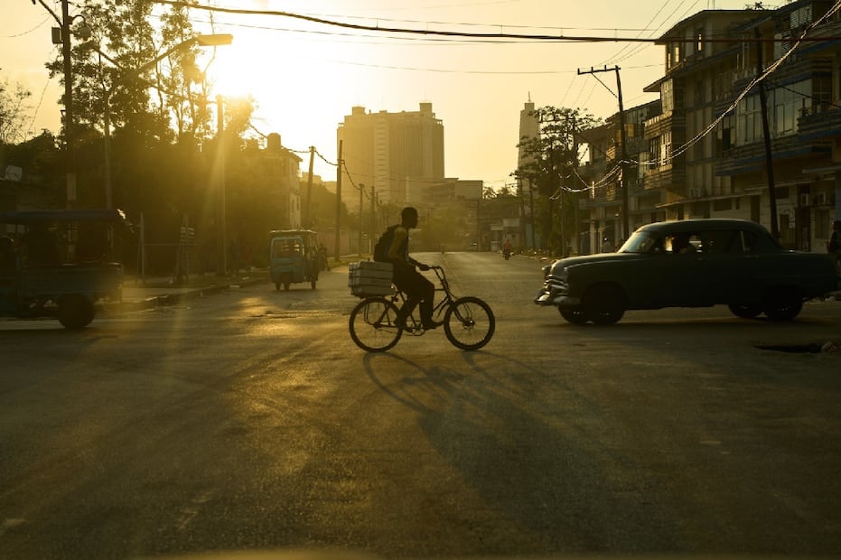 Un ciclista cruza una avenida casi vacía al atardecer, en medio de las restricciones de combustible y la baja circulación vehicular. Foto: AP.