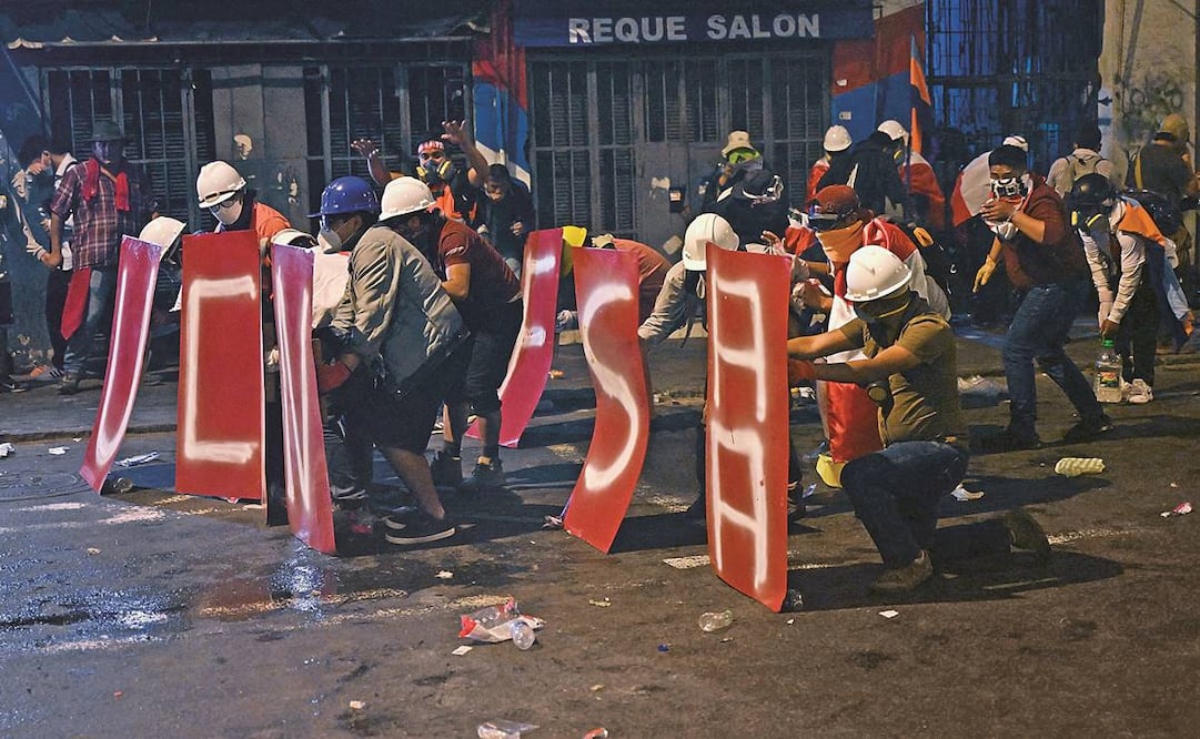 Los asistentes a una protesta contra el gobierno de Dina Boluarte se protegen con escudos improvisados durante los enfrentamientos contra la policía antidisturbios, en Lima. Foto: Ernesto Benavides/AFP