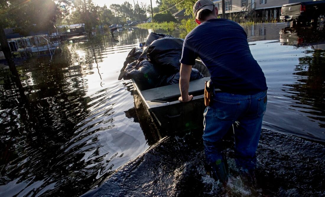 Un hombre salva sus últimas pertenencias en un bote. (AP)