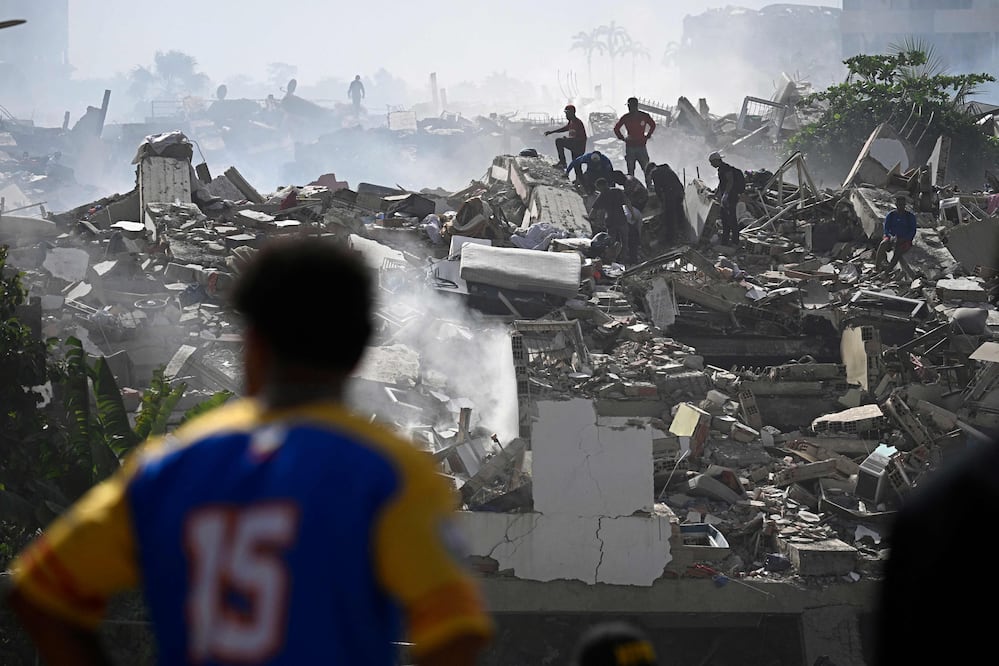 Voluntarios buscan posibles víctimas en un edificio derrumbado tras los dos terremotos que sacudieron Caraballeda, en el estado de La Guaira, a unos 40 km al noreste de Caracas, el 25 de junio de 2026. (Photo by Federico PARRA / AFP)