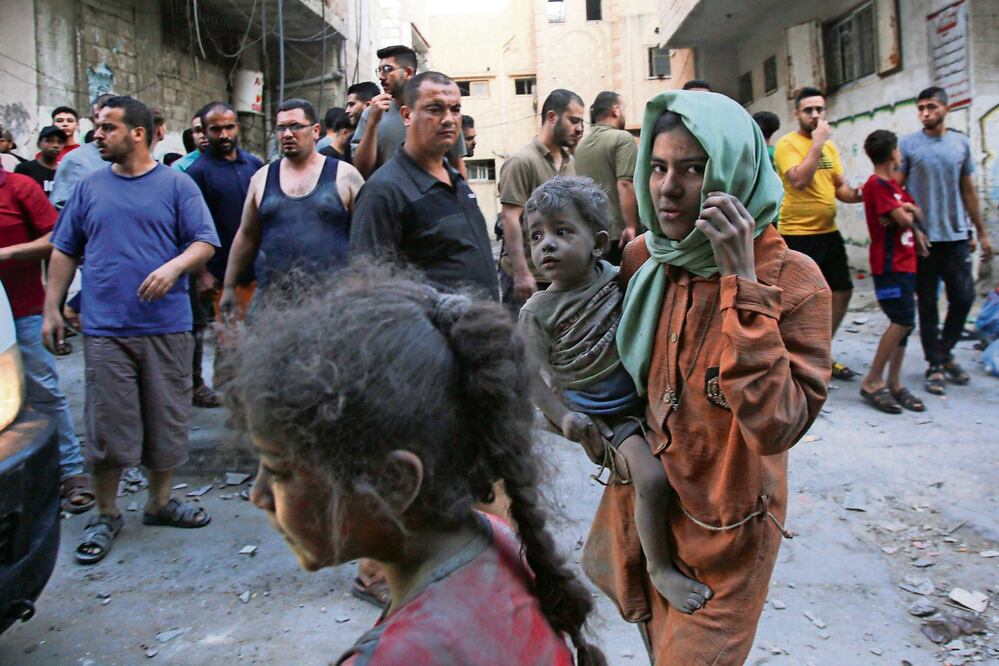 Una mujer palestina carga a un niño, este jueves, mientras continúa la guerra entre Israel y el movimiento Hamas por sexto día consecutivo en la Ciudad de Gaza. Foto: AFP