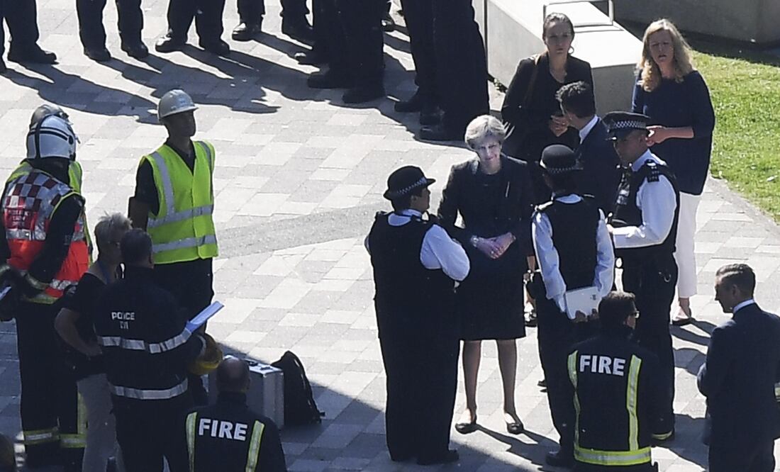 La primera ministra británica, Theresa Ma, conversa con agentes de la policía británica en el lugar donde se originó el devastador incendio
