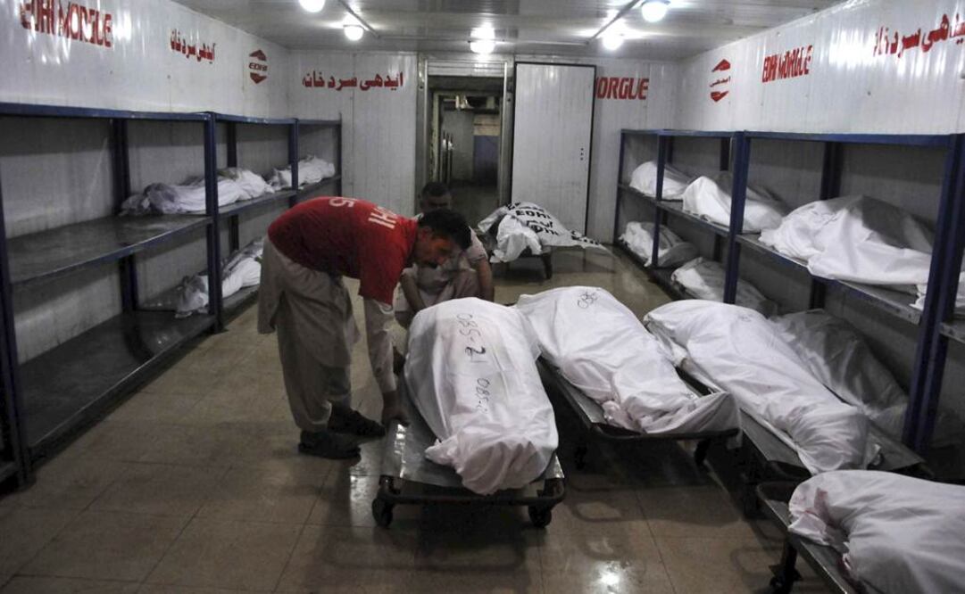 Miembros de un equipo de rescate pakistaní permanecen junto a los cadáveres de algunas de las víctimas de un tiroteo en un autobús en Karachi, Pakistán (Foto: EFE)